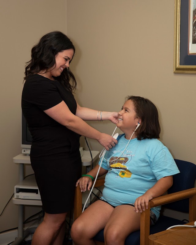 ACI audiologist fitting a hearing device on a young girl, showing our pediatric hearing care services